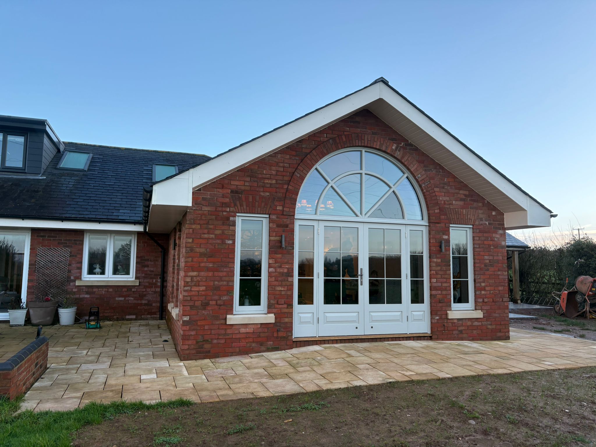 Finished brick rear extension with arched picture window and sandstone patio